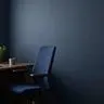 Empty modern office chair beside a tidy desk in a small business office, in deep navy and green tones, conveying a vacant role and employee turnover.